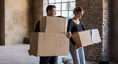 Mann und Frau tragen Umzugskartons aus einem Loft